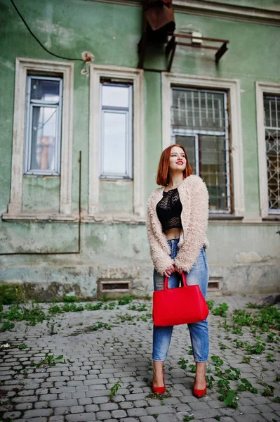 Fille aux cheveux rouges avec sac à main rouge posé à la rue de la ville . — Photo