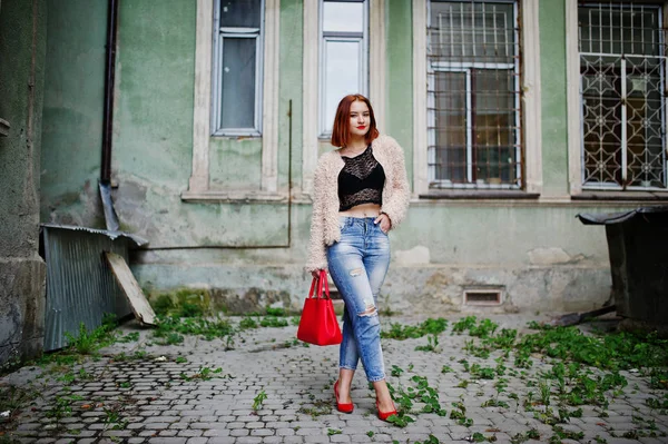 Menina de cabelos vermelhos com bolsa vermelha posou na rua da cidade . — Fotografia de Stock