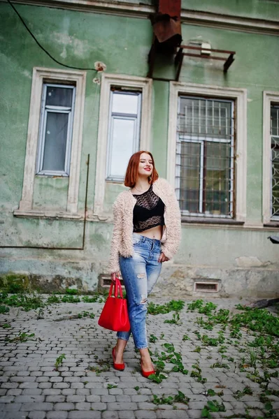 Fille aux cheveux rouges avec sac à main rouge posé à la rue de la ville . — Photo