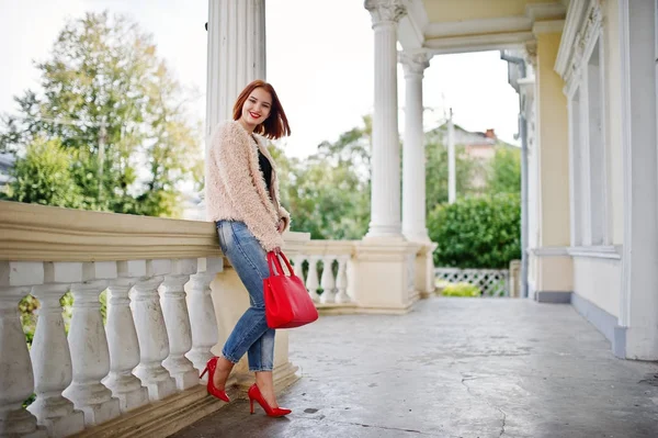 Fille aux cheveux rouges avec sac à main rouge posé près de la maison vintage . — Photo