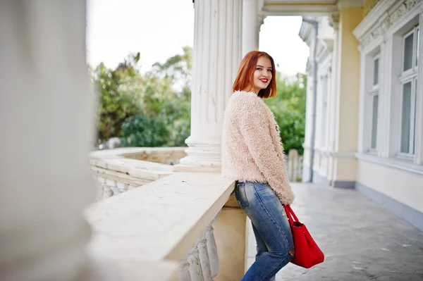 Рыжая девушка с красной сумочкой позировала возле винтажного дома . — стоковое фото