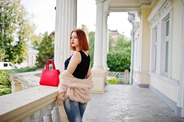 Fille aux cheveux rouges avec sac à main rouge posé près de la maison vintage . — Photo