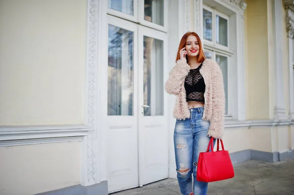 Red haired girl with red handbag posed near vintage house and sp — Stock Photo, Image