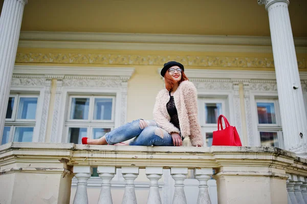 Fille aux cheveux rouges dans des lunettes et chapeau avec sac à main rouge posé près v — Photo