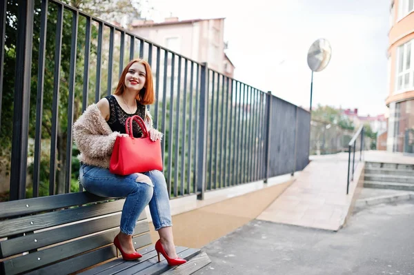 Fille aux cheveux rouges avec sac à main rouge posé sur le banc . — Photo
