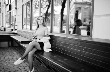 Siyah etek ve pembe ceket bankta oturan genç sarışın kız 