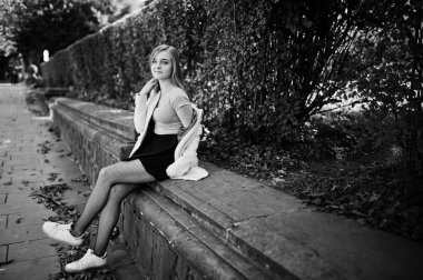 Genç sarışın kız siyah etek ve pembe ceket güneşli da poz verdi.