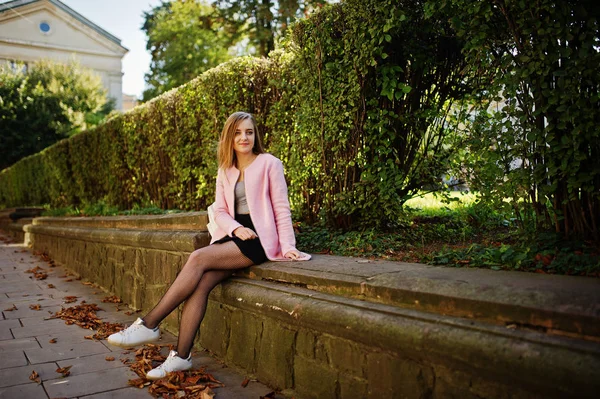 Joven rubia con falda negra y abrigo rosa posado en el soleado da — Foto de Stock