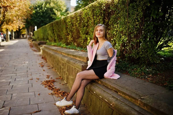 Junges blondes Mädchen in schwarzem Rock und rosa Mantel posierte bei sonnigem — Stockfoto