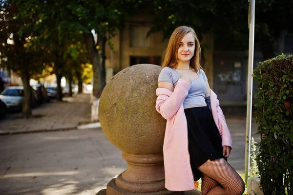 Junges blondes Mädchen in schwarzem Rock und rosa Mantel posierte bei sonnigem — Stockfoto