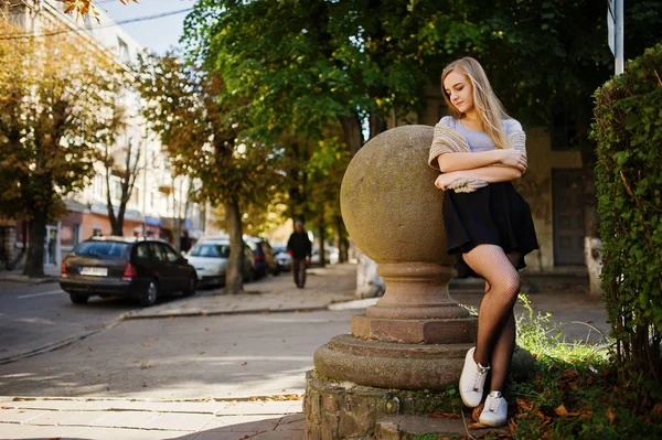 Jong blond meisje in zwarte rok met sjaal gesteld op straat van c — Stockfoto