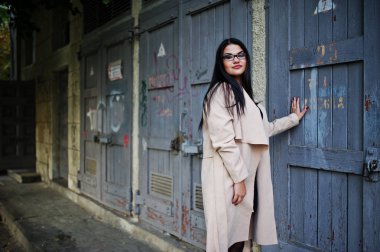 Siyah saçlı kadın gözlük ve kat idustrial sokak poz verdi..