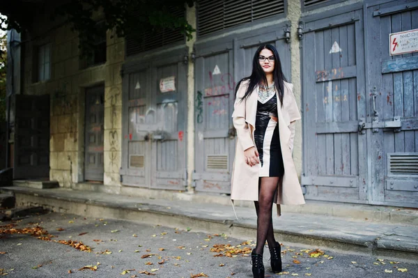 Черные волосы женщина в очках и пальто позируют на idustrial улице . — стоковое фото