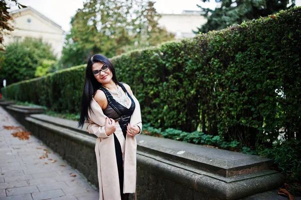 Black hair sexy woman in glasses and coat posed on street. — Stock Photo, Image