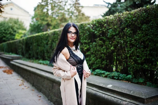 Preto cabelo sexy mulher no óculos e casaco posado no rua . — Fotografia de Stock