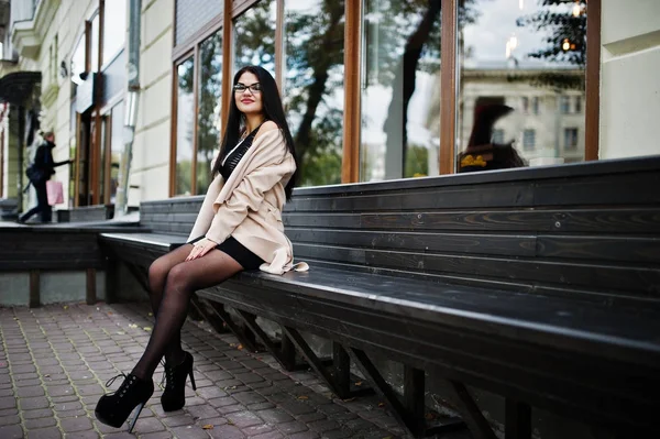 Svart hår sexig kvinna i glasögon och pälsen sitter på bänk. — Stockfoto