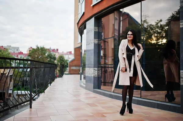 Capelli neri donna sexy in occhiali e cappotto posato contro edificio — Foto Stock