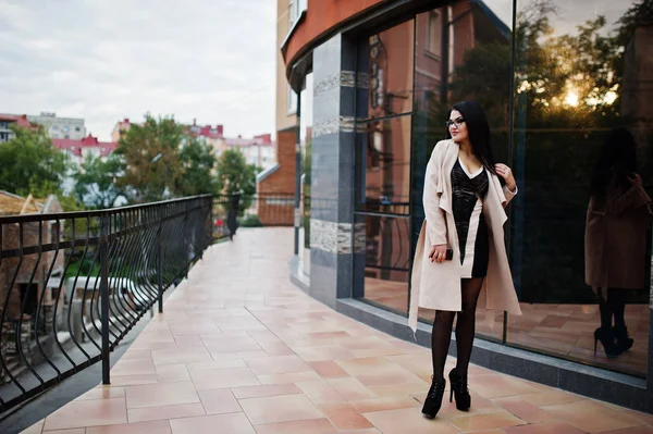 Capelli neri donna sexy in occhiali e cappotto posato contro edificio — Foto Stock
