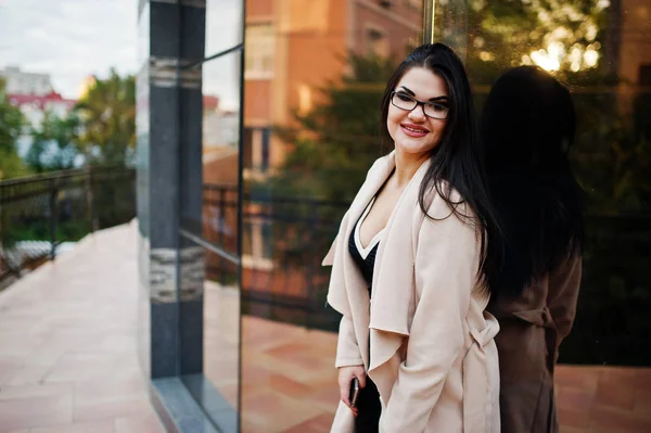 Μαύρα μαλλιά σέξι γυναίκα γυαλιά και παλτό που τίθενται ενάντια σε κτίριο — Φωτογραφία Αρχείου