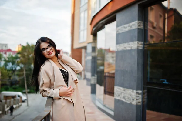 Sexy kobieta czarne włosy w okularach i płaszcz postawione przed budynku — Zdjęcie stockowe