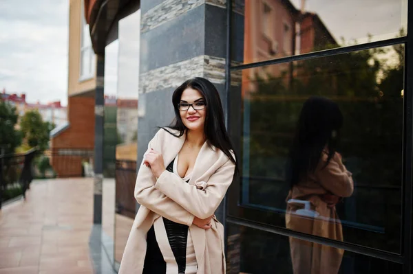 Pelo negro sexy mujer en gafas y abrigo posado contra la construcción —  Fotos de Stock