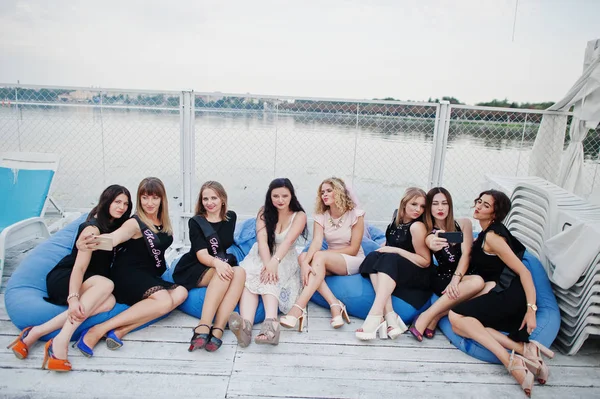 Grupo de 8 meninas usam em preto e 2 noivas na festa das galinhas sentado — Fotografia de Stock