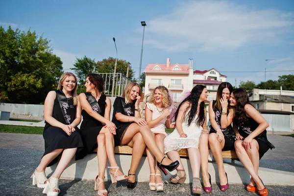 Grupa 7 dziewczyn nosi na czarny i 2 narzeczonych, siedząc na ławce i — Zdjęcie stockowe