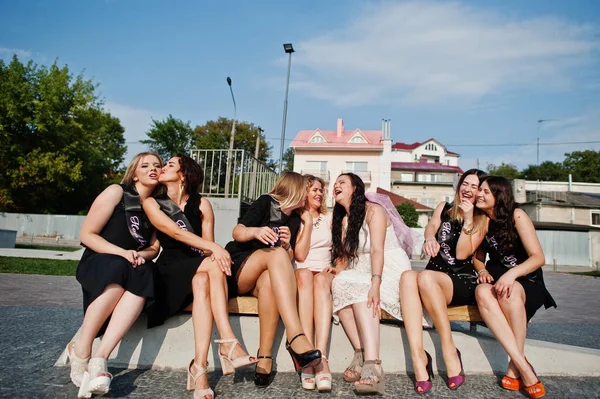 Gruppo di 7 ragazze vestite di nero e 2 spose sedute su panchina e — Foto Stock