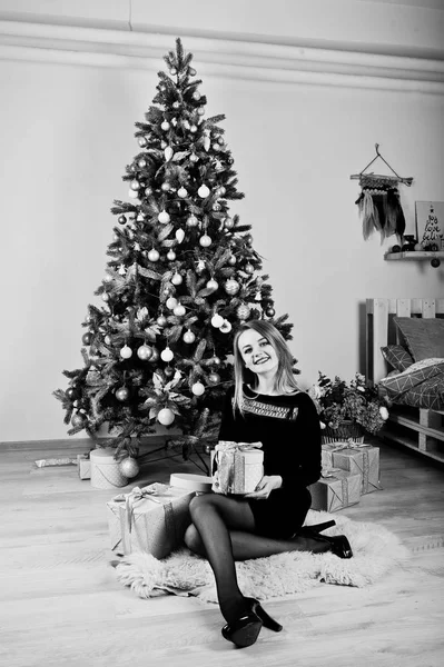 Roztomilá blondýnka na černé šaty proti novoroční strom s Chrisem — Stock fotografie
