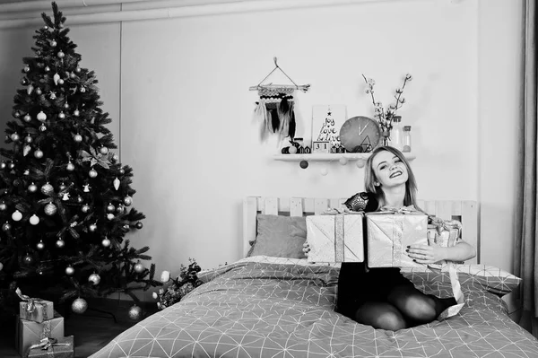 선물과 함께 침대에 누워 검은 드레스에 귀여운 금발 여자 상자 ag — 스톡 사진