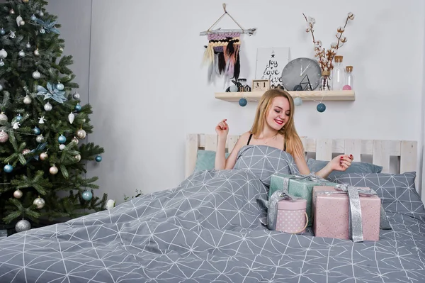 Schattige blonde meisje op zwarte beha liggend op bed met geschenken dozen agai — Stockfoto