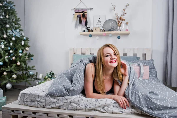 Jolie fille blonde sur le soutien-gorge noir couché sur le lit avec des boîtes-cadeaux agai — Photo