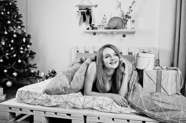 Jolie fille blonde sur le soutien-gorge noir couché sur le lit avec des boîtes-cadeaux agai — Photo