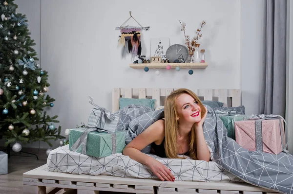Ładna Blondynka na czarny stanik leży na łóżku z agai pola prezenty — Zdjęcie stockowe