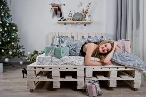 Menina loira bonito no sutiã preto deitado na cama com caixas de presentes agai — Fotografia de Stock