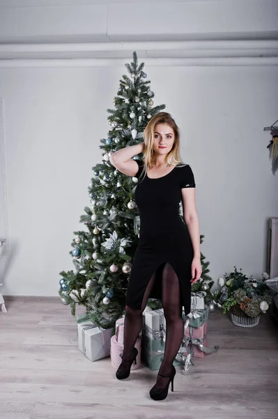 Blond dziewczyna w czarnej sukni, jakie w pobliżu drzewa nowy rok z christm — Zdjęcie stockowe