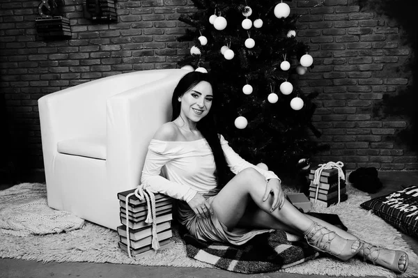 Brunetka v šaty představuje poblíž novoroční strom s vánoční d — Stock fotografie