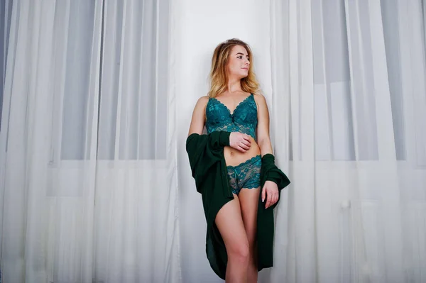 Sexy modelo loira em lingerie verde contra cortinas em branco ro — Fotografia de Stock