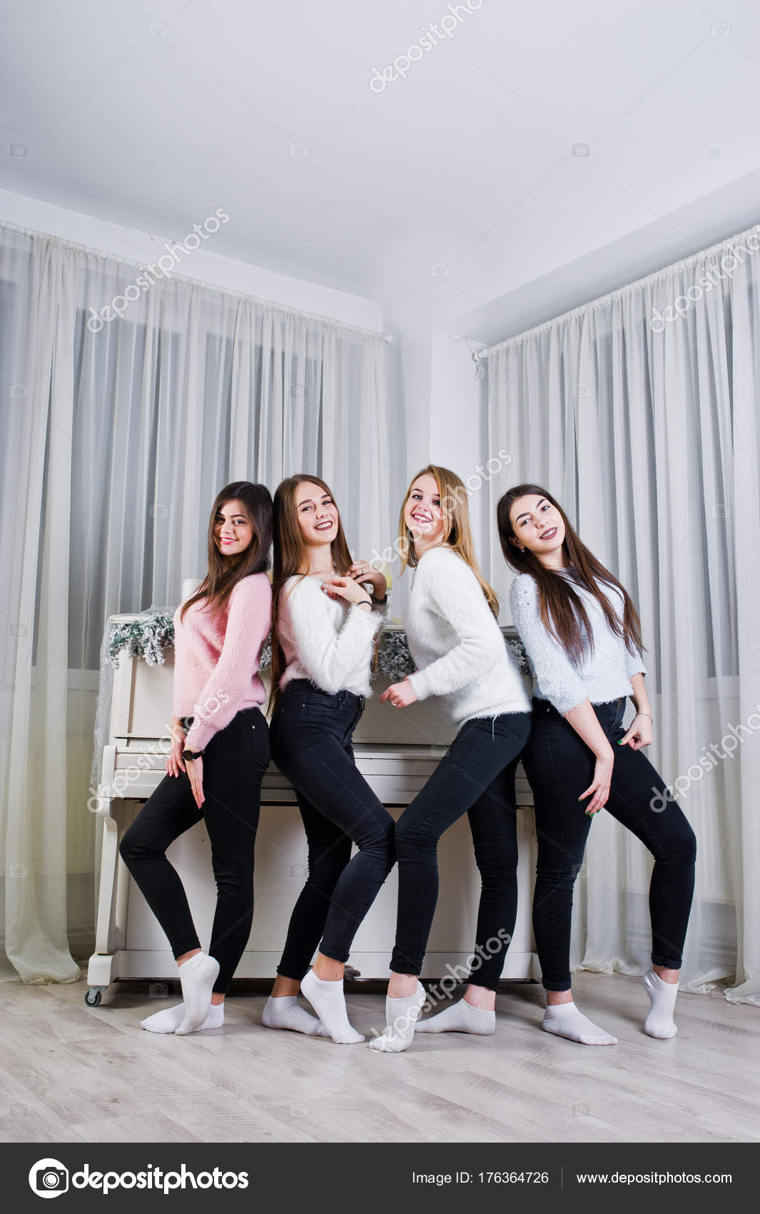 Four cute friends girls wear on warm sweaters and black pants ag ...