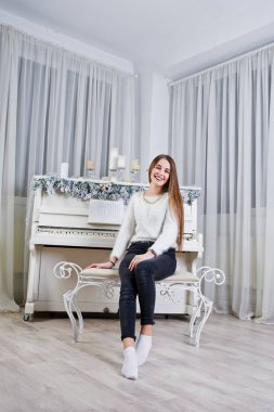 Sevimli kız giymek sıcak kazak ve siyah pantolon eski pian karşı