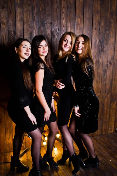 Vier süße Freundinnen tragen schwarze Kleider gegen großes Licht — Stockfoto