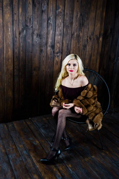 Ξανθιά κοπέλα Elegante φορούν γούνα παλτό κάθεται σε καρέκλα στο studio — Φωτογραφία Αρχείου