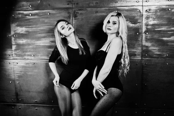 Dos chicas rubias elegantes usan en combi vestido posado contra stee — Foto de Stock