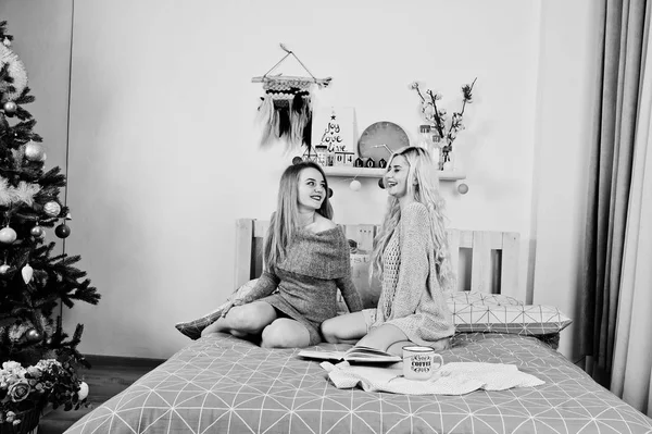Dvě elegante blond dívka opotřebení na teplé tunika sedí na posteli znovu — Stock fotografie