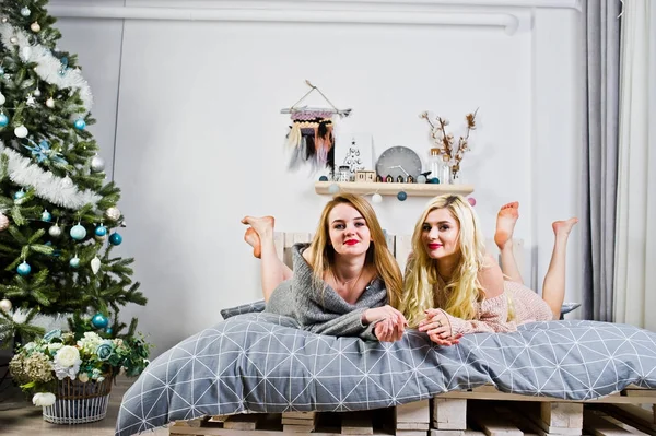 Dvě elegante blond dívka opotřebení na teplé tunika sedí na posteli znovu — Stock fotografie