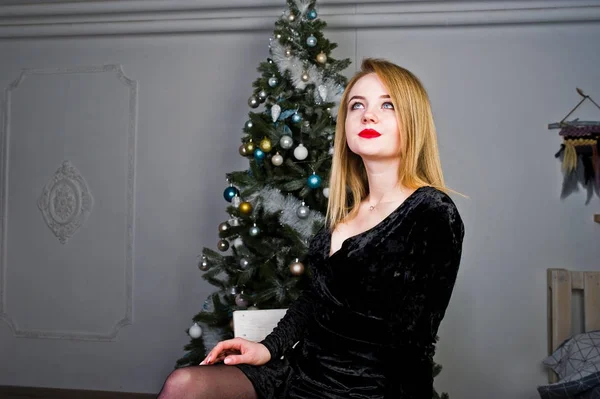 Elegante ragazza bionda indossare il vestito nero contro il nuovo albero di anno w — Foto Stock