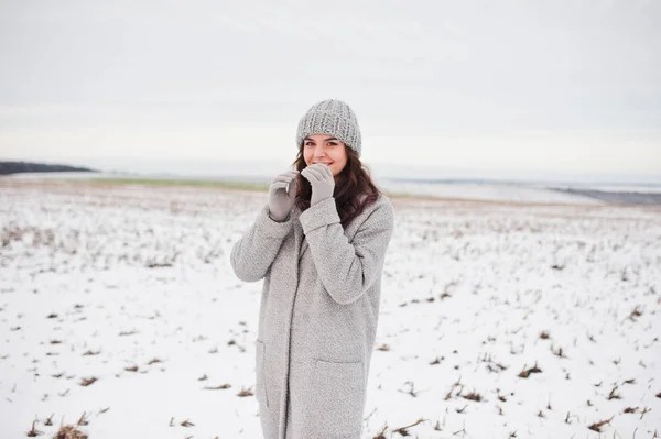 Delikatny dziewczynka w szary płaszcz i kapelusz przeciwko krajobraz snow. — Zdjęcie stockowe