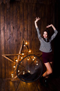 Ahşap arka plan ile stüdyoda ışık yıldız karşı yöneltilen kız.