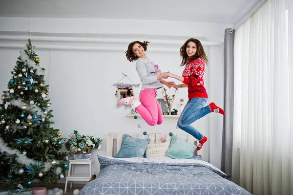 Zwei Freundinnen tragen Winterpullover und amüsieren sich auf dem Bett bei roo — Stockfoto