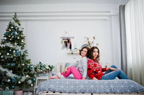 Due amiche indossano maglioni invernali divertendosi sul letto a roo — Foto Stock